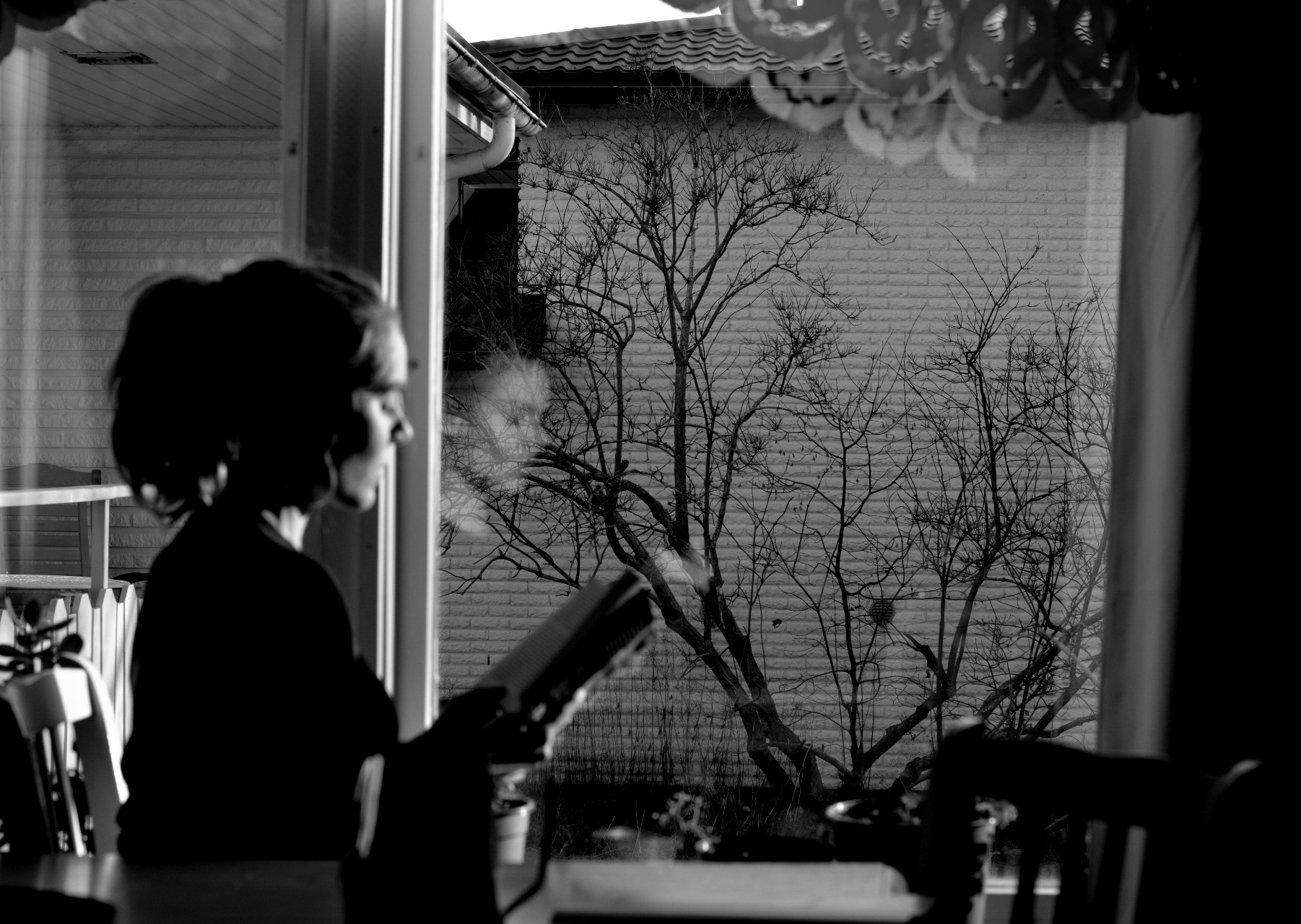 Ulrika Nettelblad läser en bok, svartvitt, framför ett fönster.