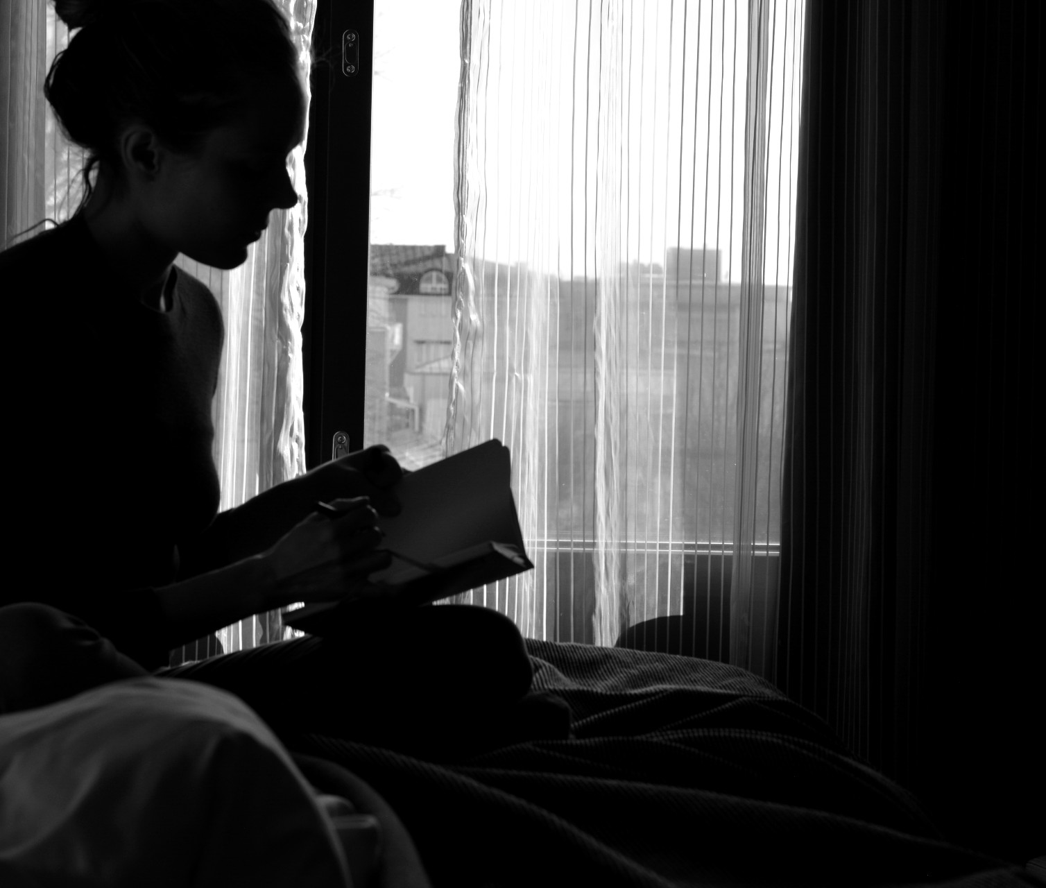Ulrika Nettelblad läser bok på Hotell Pommern. Svartvit bild, motljus.
