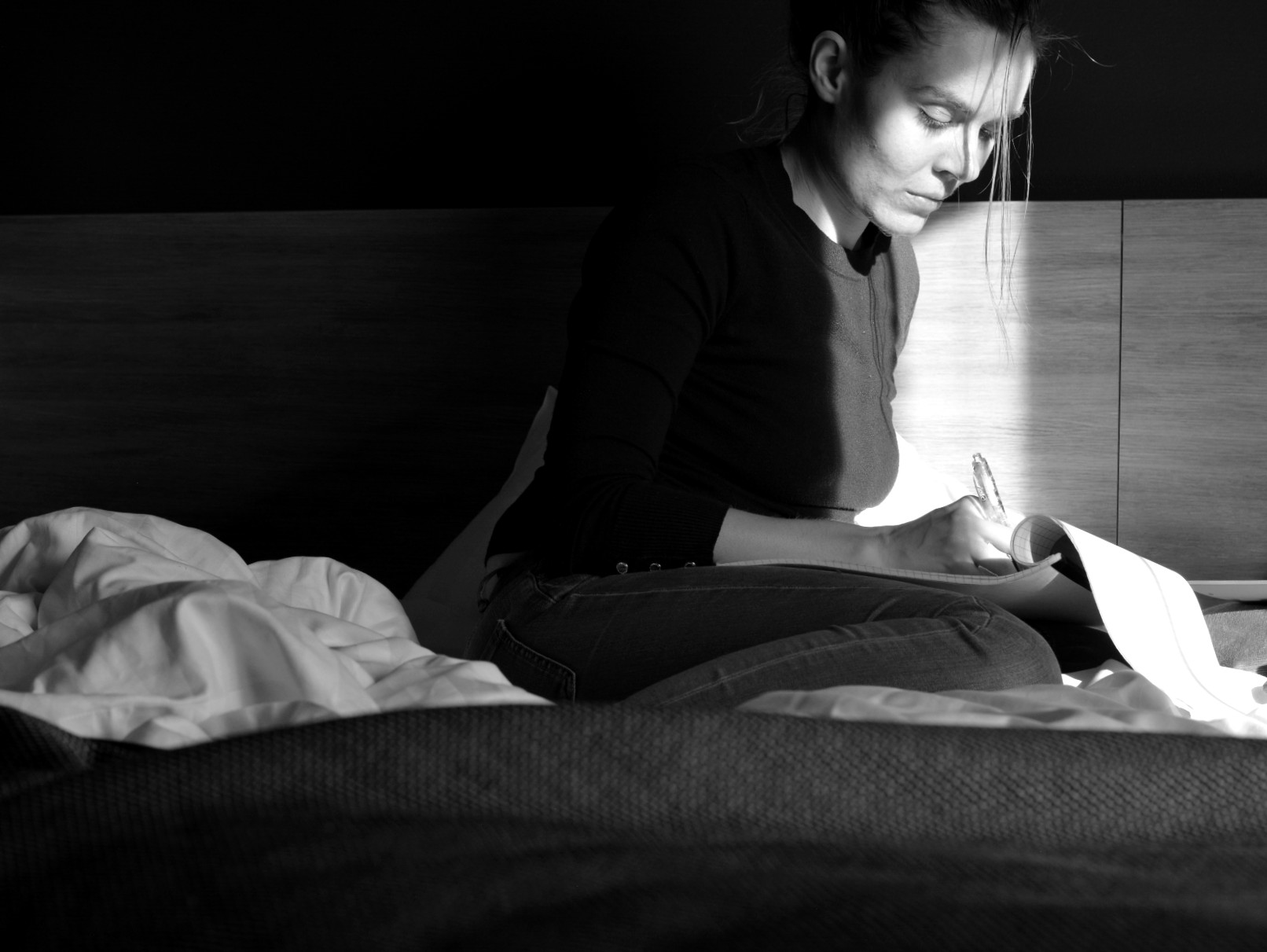 Ulrika Nettelblad skriver på laptop i skarpt solljus i hotellrum. Svartvit bild.
