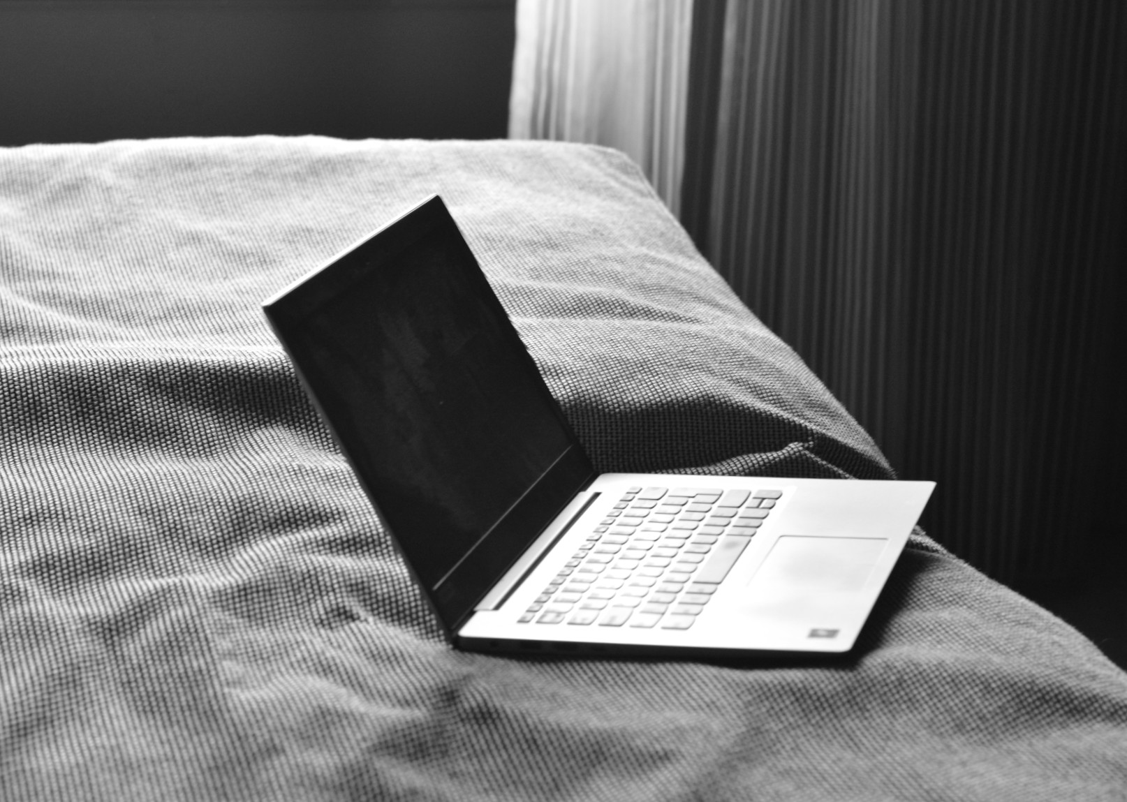 Svartvit bild på laptop på säng.