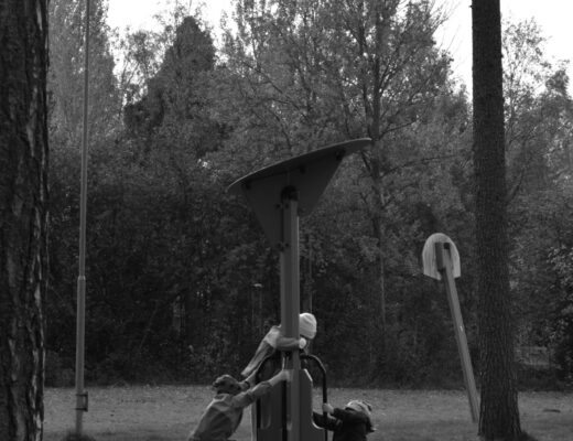 Svartvit bild på tre barn på snurrgunga i lekpark.