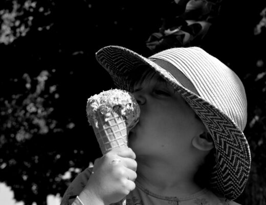 Liten flicka i hatt äter glass i motljus. svartvitt