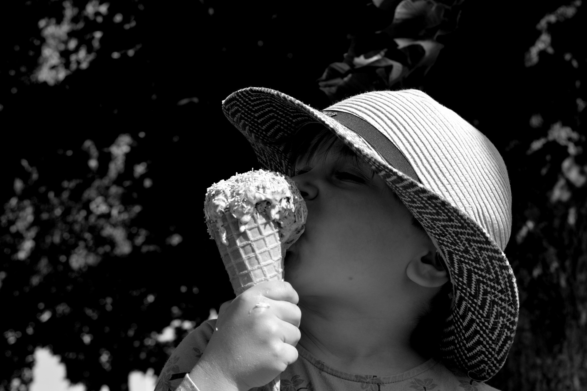 Liten flicka i hatt äter glass i motljus. svartvitt