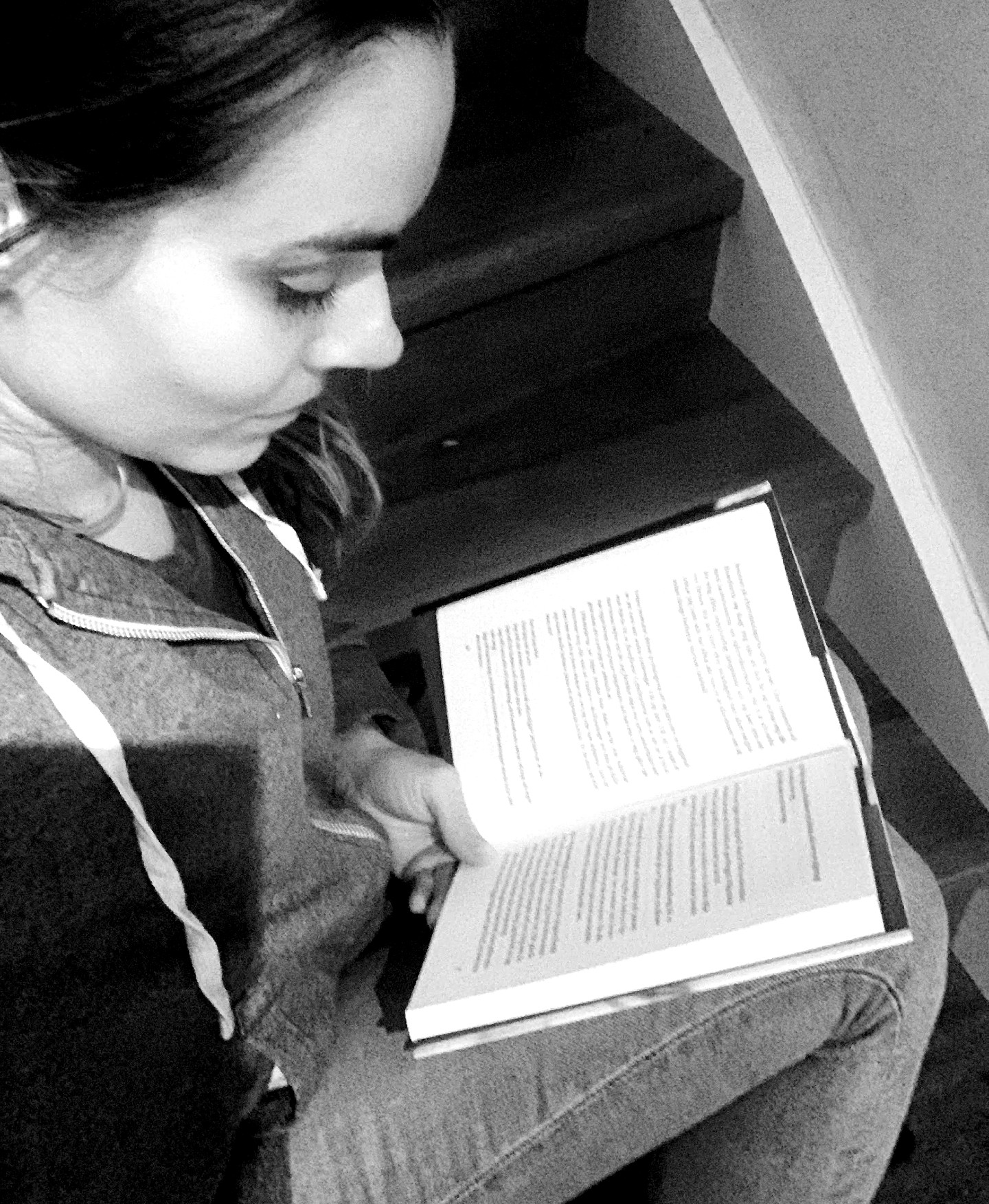 Bild på kvinna som läser bok i trappa. svartvitt