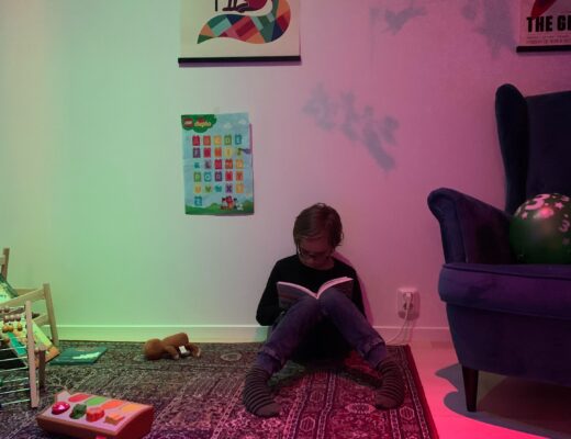 Pojke läser bok i barnrum med discoljus